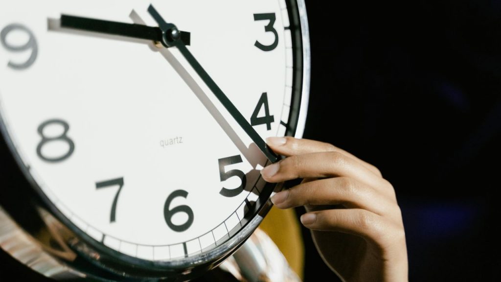 Mano che sposta le lancette di un orologio